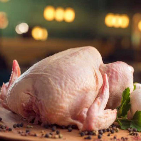 Ολόκληρο κοτόπουλο Ιωαννίνων σε ξύλο κοπής, με λεμόνια και μυρωδικά, έτοιμο για μαγείρεμα.