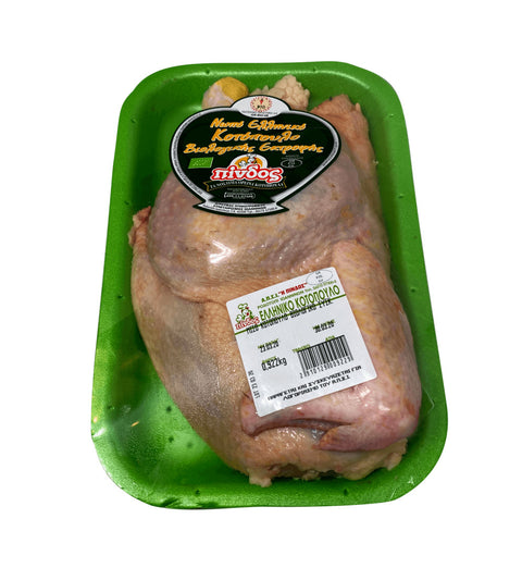 Βιολογικό κοτόπουλο Πίνδος, ολόκληρο, σε ξύλο κοπής, έτοιμο για μαγείρεμα, με λεμόνια και φρέσκα μυρωδικά δίπλα.